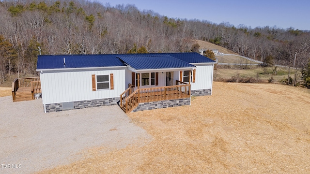 manufactured / mobile home featuring driveway, metal roof, crawl space, a porch, and a wooded view