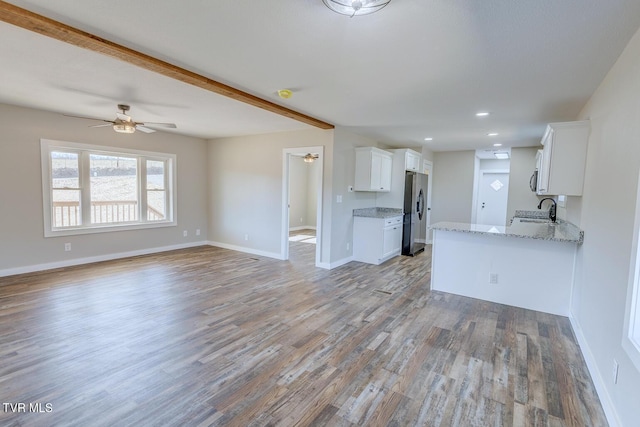 kitchen featuring light stone counters, light wood-style floors, open floor plan, white cabinets, and stainless steel refrigerator with ice dispenser