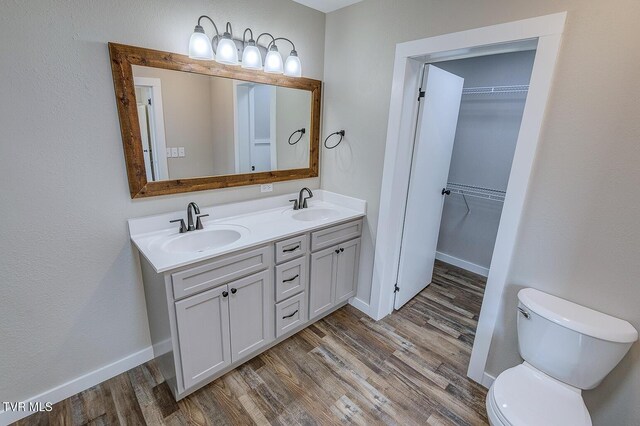 bathroom with toilet, a sink, and wood finished floors