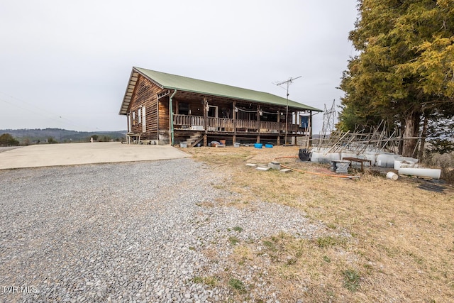 view of front of house with covered porch, driveway, and metal roof