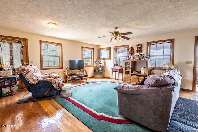 living room featuring a textured ceiling, baseboards, ceiling fan, and hardwood / wood-style flooring