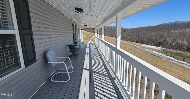 wooden deck featuring a porch and a wooded view