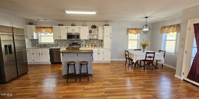 kitchen with open shelves, stainless steel appliances, white cabinetry, a kitchen island, and a sink