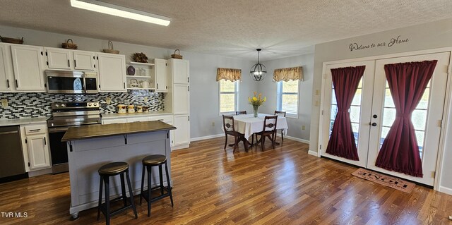 kitchen with dark wood-style floors, french doors, open shelves, stainless steel appliances, and white cabinets