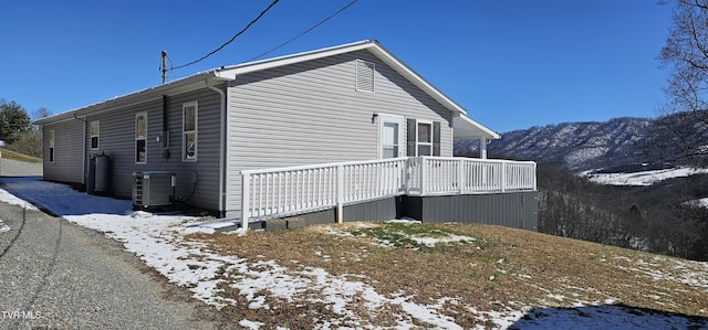 snow covered property with a deck and central AC unit