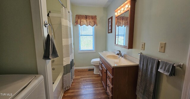 bathroom featuring toilet, wood finished floors, vanity, baseboards, and washer / dryer