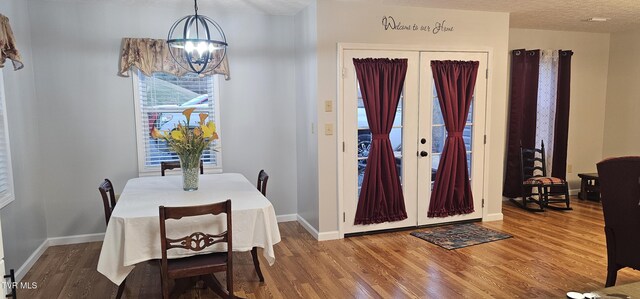 dining space featuring baseboards, a notable chandelier, and wood finished floors