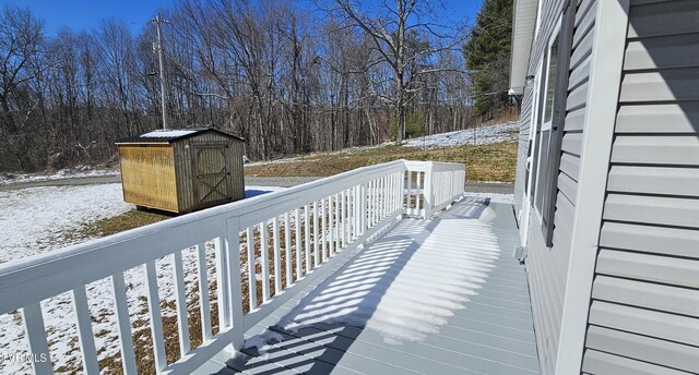 snow covered deck featuring an outbuilding and a shed