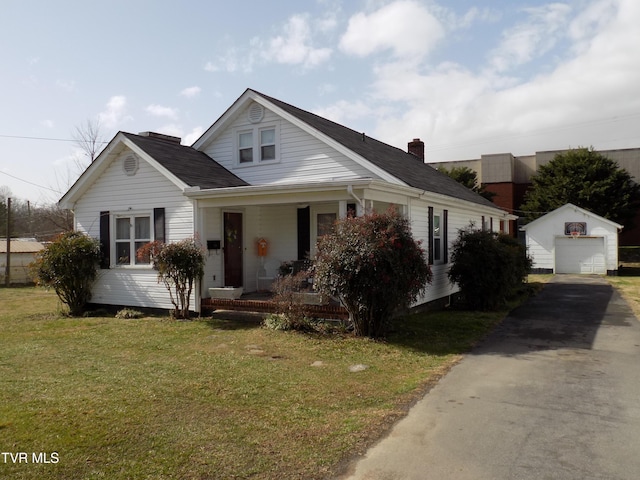 bungalow-style home featuring an outbuilding, covered porch, a garage, driveway, and a front lawn