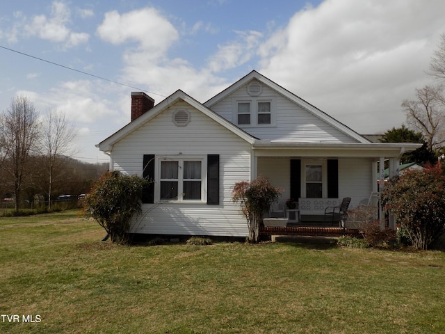 bungalow-style home with covered porch, a front lawn, and a chimney