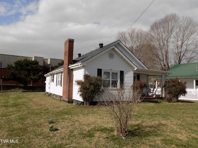 view of front of property featuring covered porch, a chimney, and a front lawn