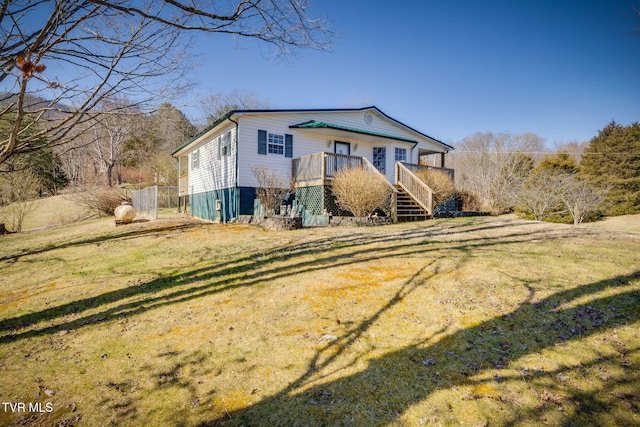 view of front of property featuring stairs, a front yard, and a wooden deck