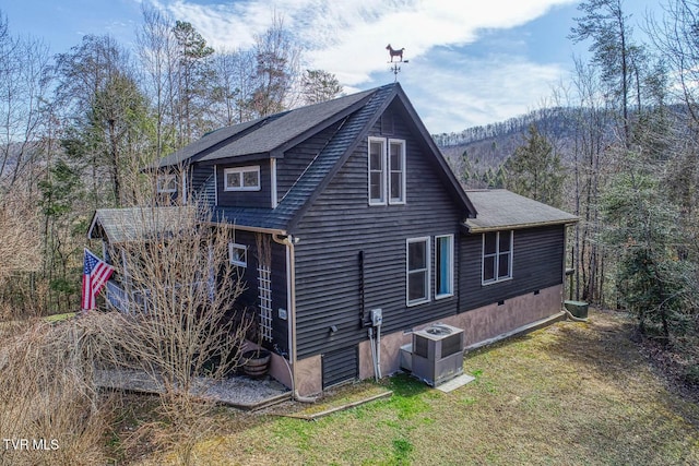 rear view of property with a shingled roof, central AC, and a yard