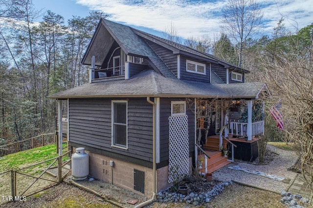 view of front of property with a shingled roof, fence, and a balcony