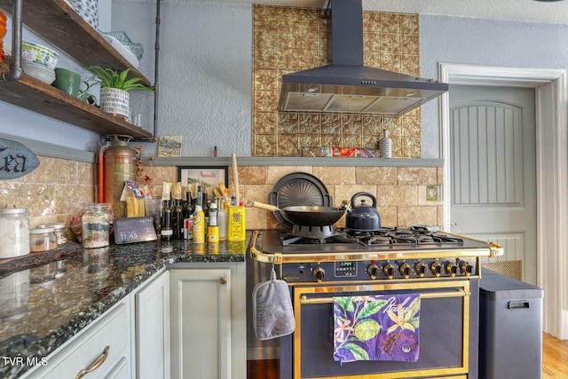 kitchen featuring range hood, open shelves, high end stainless steel range, backsplash, and dark stone counters