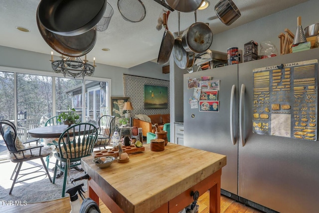 kitchen featuring light wood finished floors, butcher block countertops, and freestanding refrigerator