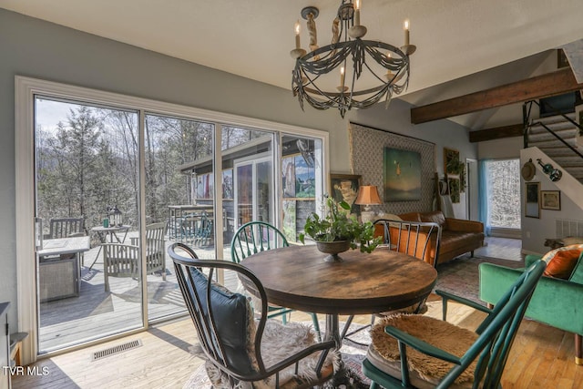 dining area featuring vaulted ceiling with beams, a notable chandelier, visible vents, stairs, and light wood finished floors