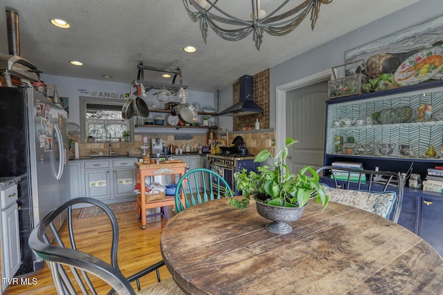 dining space featuring light wood-style flooring, a textured ceiling, and recessed lighting