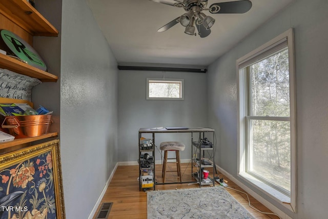 interior space with a ceiling fan, wood finished floors, visible vents, and baseboards