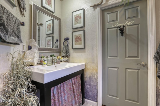 bathroom featuring a textured wall and vanity