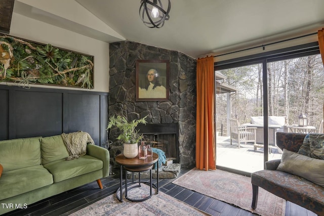 living area featuring lofted ceiling, a fireplace, wood finished floors, and wainscoting