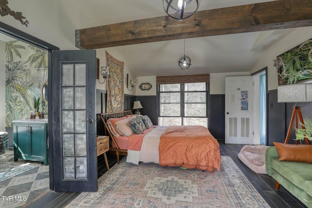 bedroom featuring a wainscoted wall, wood finished floors, and vaulted ceiling with beams