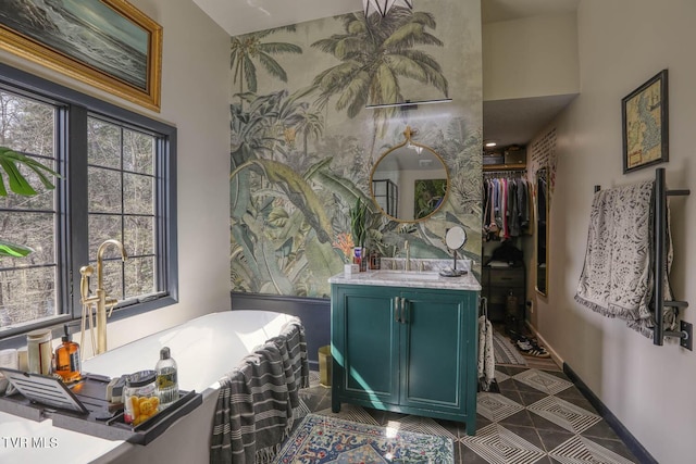 bathroom with a soaking tub, vanity, baseboards, and tile patterned floors