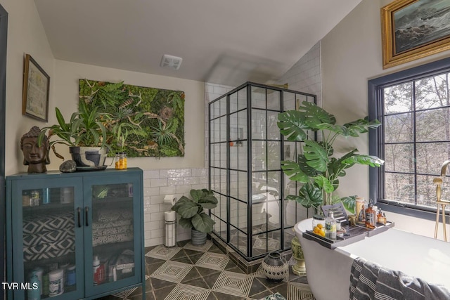 interior space with visible vents, tile walls, vaulted ceiling, a soaking tub, and a shower stall