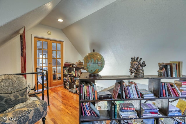 living area with lofted ceiling, french doors, and wood finished floors