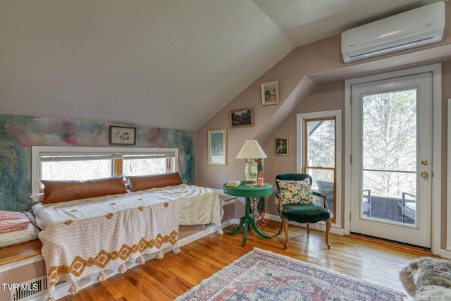 bedroom with lofted ceiling, access to outside, an AC wall unit, and wood finished floors