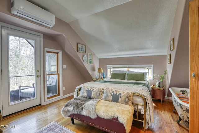 bedroom with lofted ceiling, wood finished floors, baseboards, access to outside, and a wall mounted AC