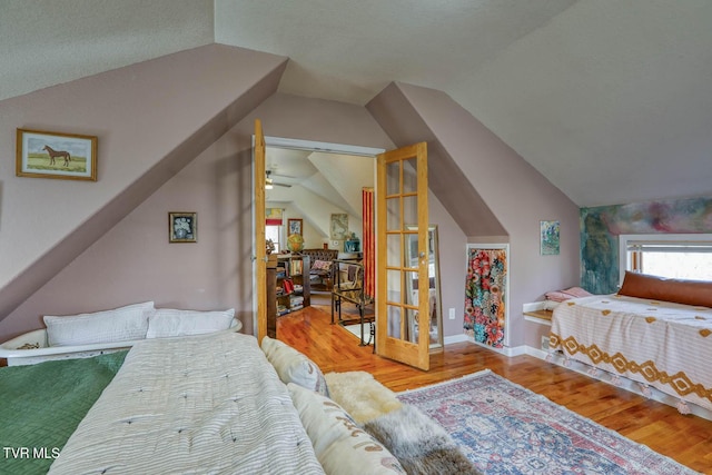 bedroom with vaulted ceiling, baseboards, and wood finished floors