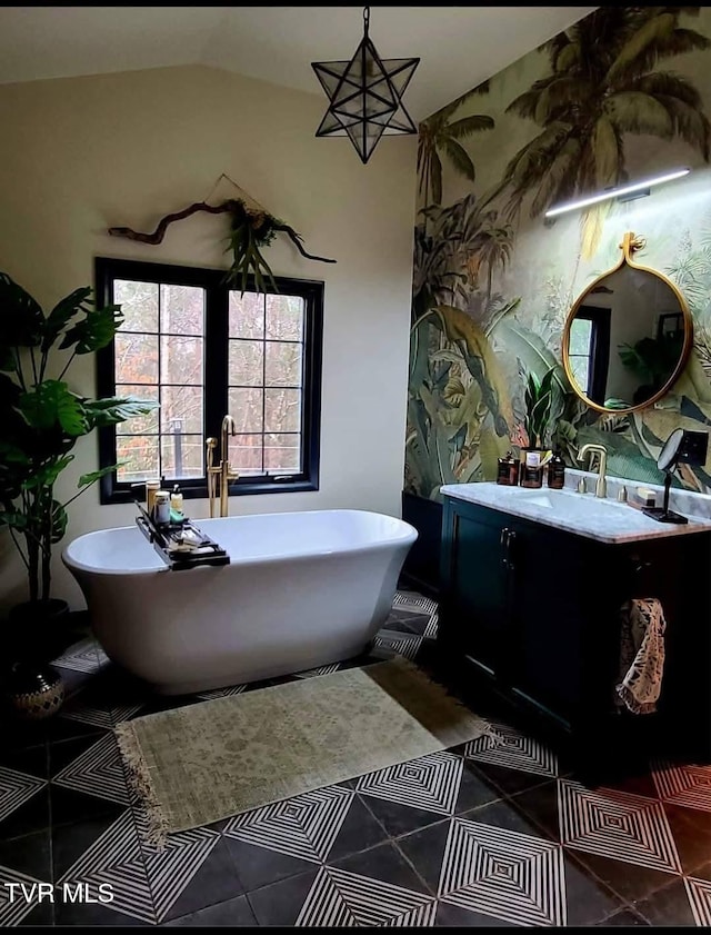 full bathroom featuring tile patterned flooring, a soaking tub, vaulted ceiling, and vanity