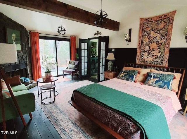 bedroom with wood finished floors, beam ceiling, and access to exterior