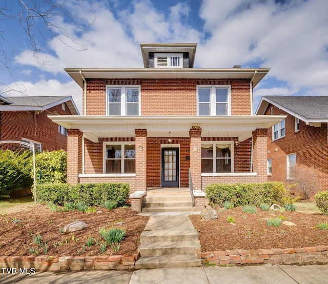 american foursquare style home featuring brick siding and covered porch