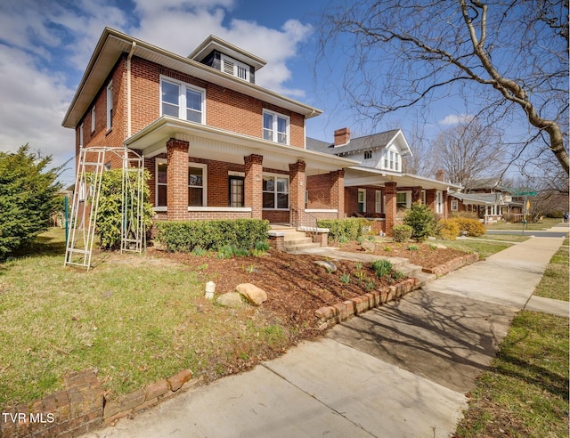 traditional style home with brick siding, covered porch, and a front yard