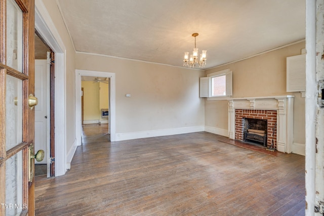 unfurnished living room with wood finished floors, crown molding, a notable chandelier, and a fireplace