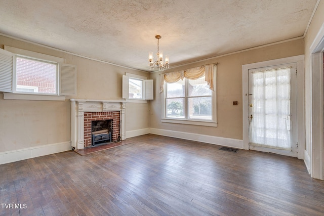 unfurnished living room featuring hardwood / wood-style floors, a brick fireplace, visible vents, and a textured ceiling