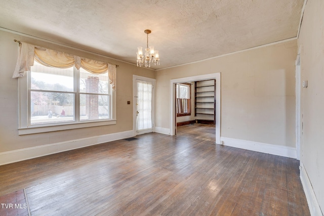 unfurnished room featuring visible vents, dark wood-type flooring, a notable chandelier, crown molding, and baseboards