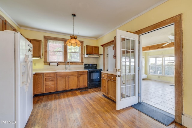 kitchen featuring brown cabinets, black range with electric stovetop, a sink, white refrigerator with ice dispenser, and light countertops