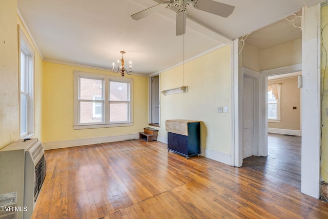 unfurnished room with hardwood / wood-style flooring, heating unit, an inviting chandelier, crown molding, and baseboards