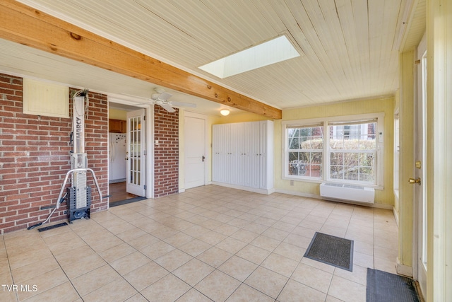 unfurnished sunroom with a ceiling fan, beam ceiling, a skylight, and wood ceiling