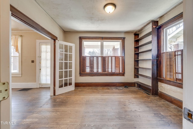 empty room featuring baseboards, a textured ceiling, and wood finished floors