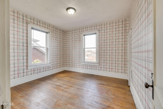 unfurnished room with wallpapered walls, baseboards, and hardwood / wood-style floors