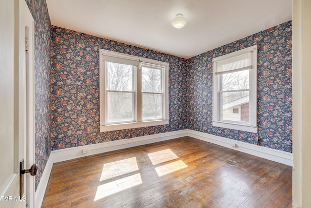 unfurnished room with wallpapered walls, baseboards, and wood-type flooring