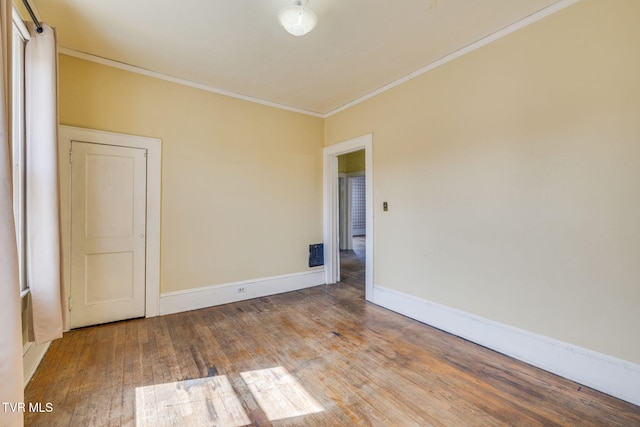 empty room with visible vents, hardwood / wood-style flooring, baseboards, and ornamental molding