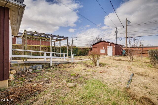 view of yard with a shed, a pergola, an outdoor structure, and fence