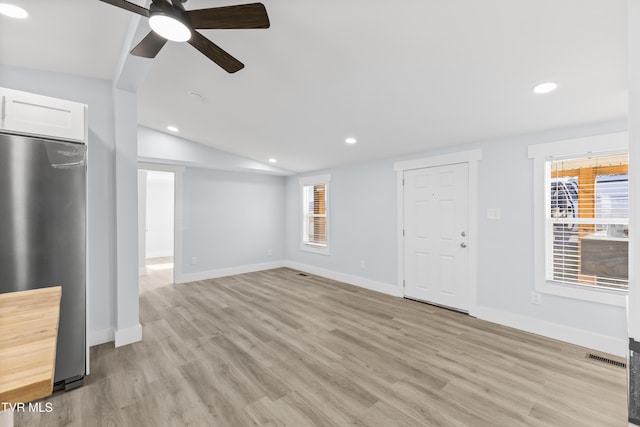 unfurnished living room with light wood-style flooring, vaulted ceiling, a wealth of natural light, and recessed lighting