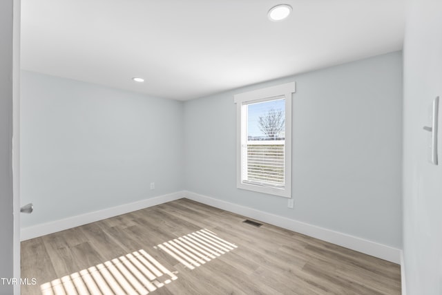 empty room with baseboards, visible vents, wood finished floors, and recessed lighting