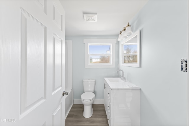 half bath with toilet, wood finished floors, visible vents, vanity, and baseboards